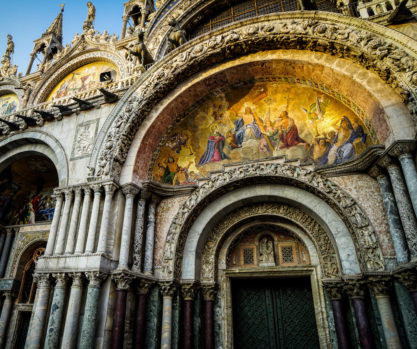 Basilica di San Marco : The setting sun lights up the golden mosaic on the central portal