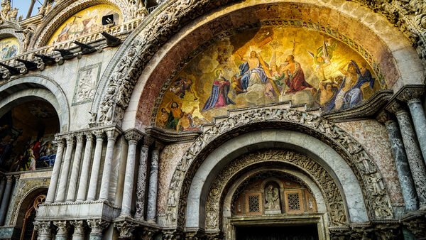 Basilica di San Marco : The setting sun lights up the golden mosaic on the central portal