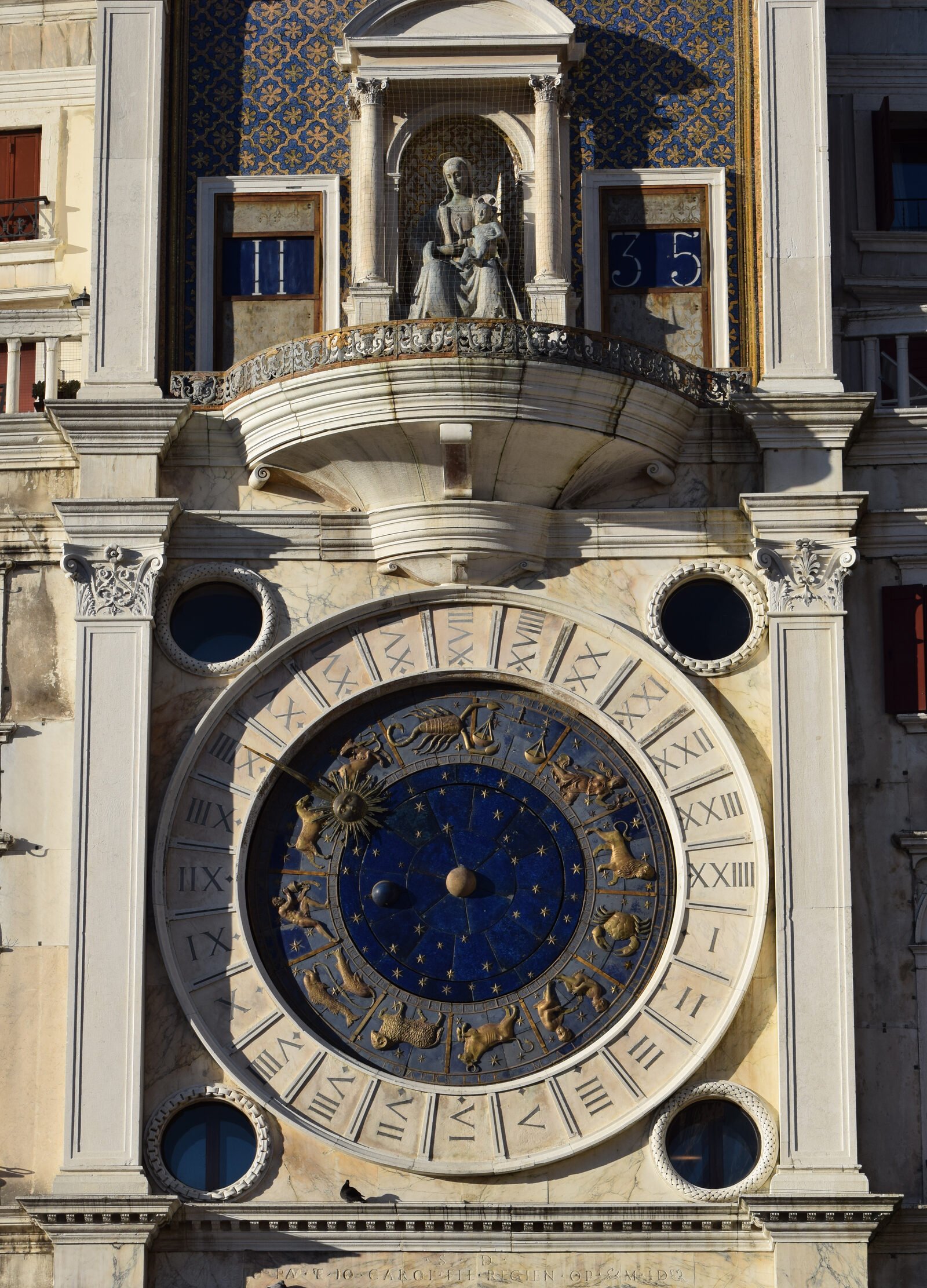 Torre dell'Orologio : The 24-hour dial with zodiac signs, above which sits the Virgin and child statue flanked by two barrels displaying hours and minutes